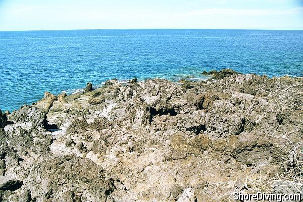 By careful traversing the lava;  you'll find a ledge that will ease you into the water.  Of course, don't attempt this entry except on a calm day.