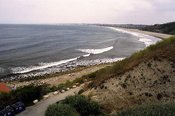 A long, sandy beach lies beyond the rocky diving area.