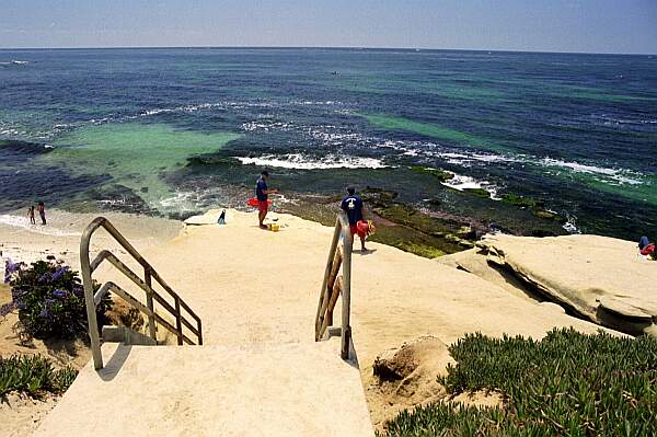 The stairs take you down to the rocks, but watch your step thereafter.  You'll need to make a small jump to the sand.