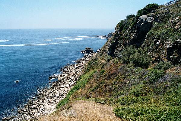 The trail appears to precariously wrap around the cliff, but it is well-maintained and safe.