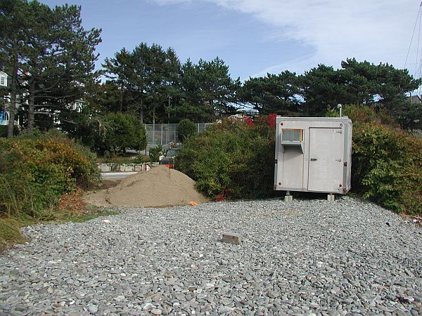 The parking is well packed gravel.  The mound of dirt at the entrance is temporary.  At the time of this writing, a seawall further down the road was almost complete with a set of stairs down to the water.
